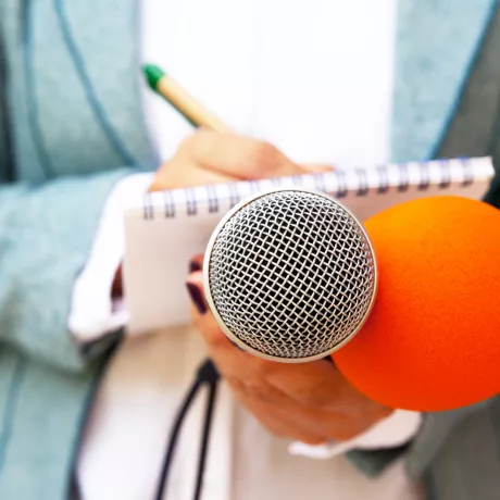 reporter taking notes holding microphone