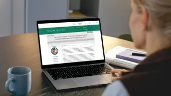 Woman looks at a laptop screen showing a news article