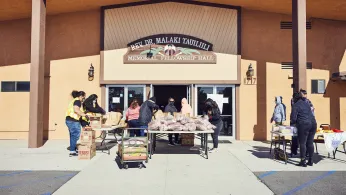 Volunteers pack food into paper bags for distribution to Native Hawaiians and Pacific Islanders